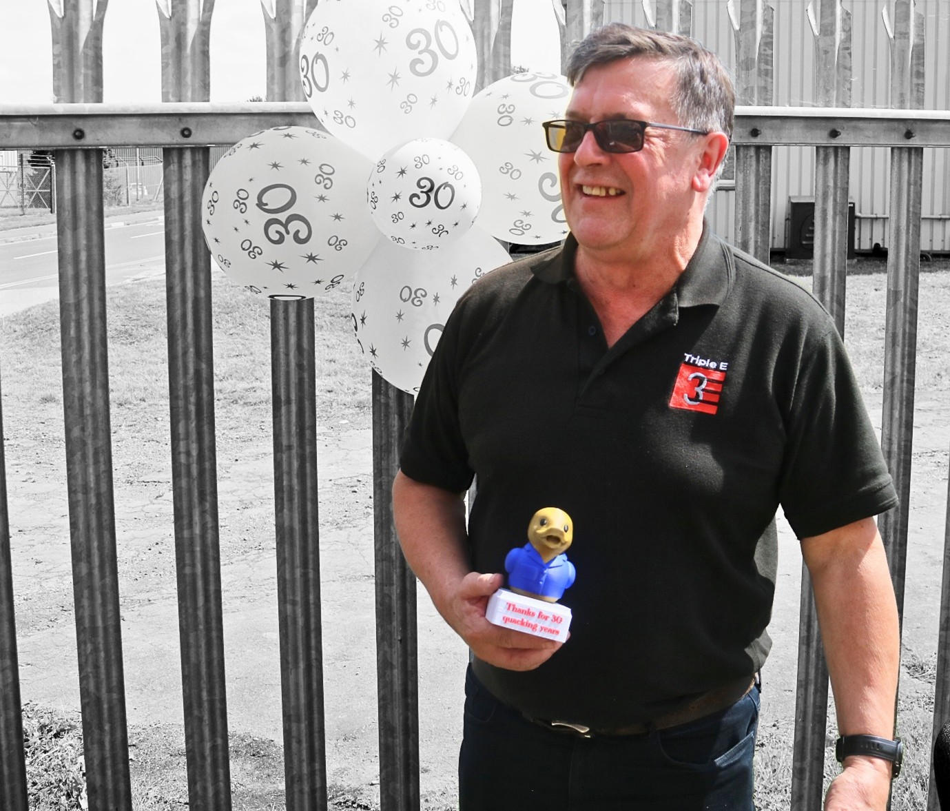 barry thorley smiling in triple e uniform holding trophy for 30 years of service at triple e